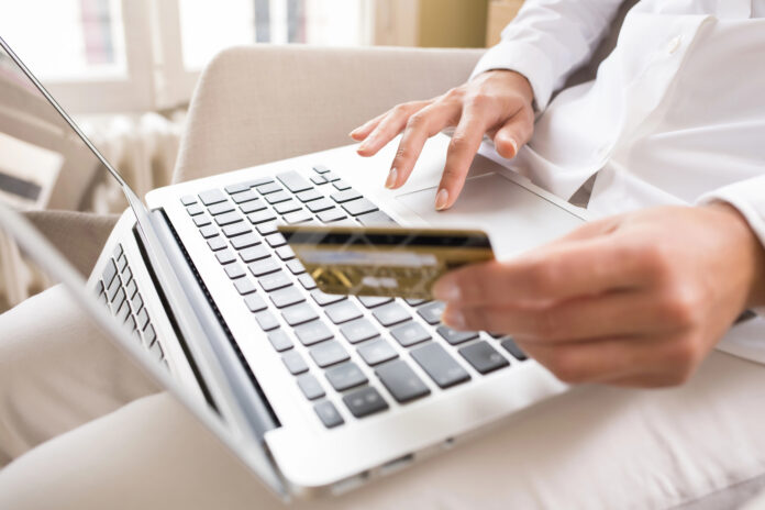 photo-of-woman-holding-bank-card-pays-online-using-laptop