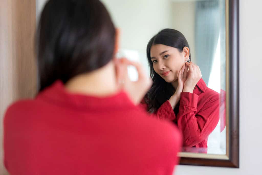 photo-of-woman-putting-on-earrings-in-mirror
