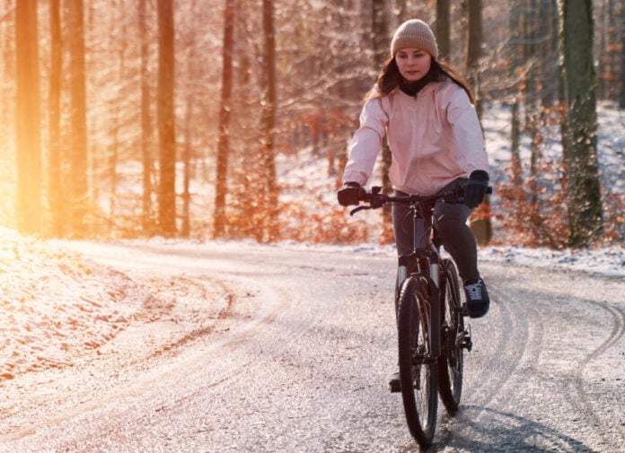 photo-of-woman-biking-through-snow-with-morning-light-behind-her