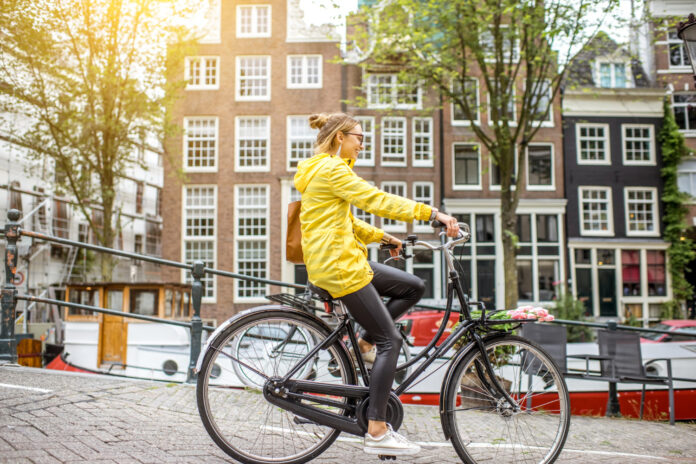 photo-of-woman-riding-bike-on-amsterdam-streets-with-yellow-raincoat