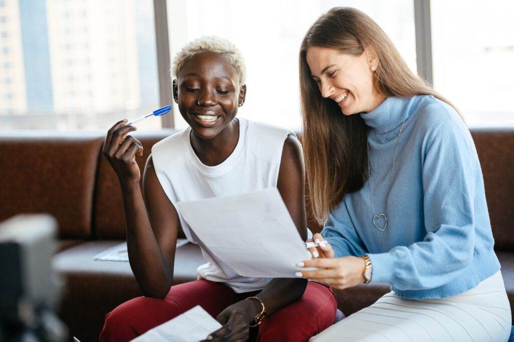 photo-of-woman-signing-work-contract-helped-by-colleague-to-understand