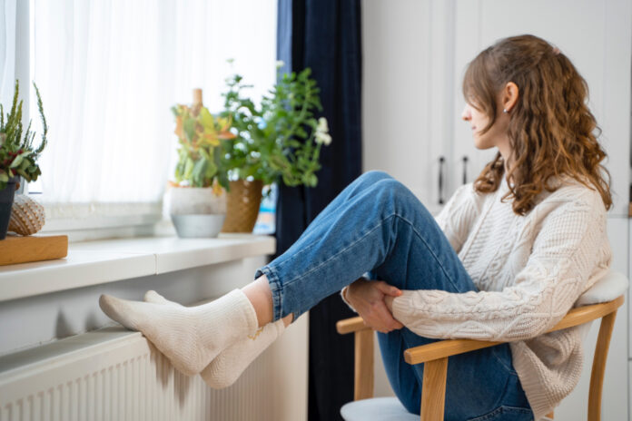 photo-of-woman-in-sweater-sitting-with-feet-on-radiator