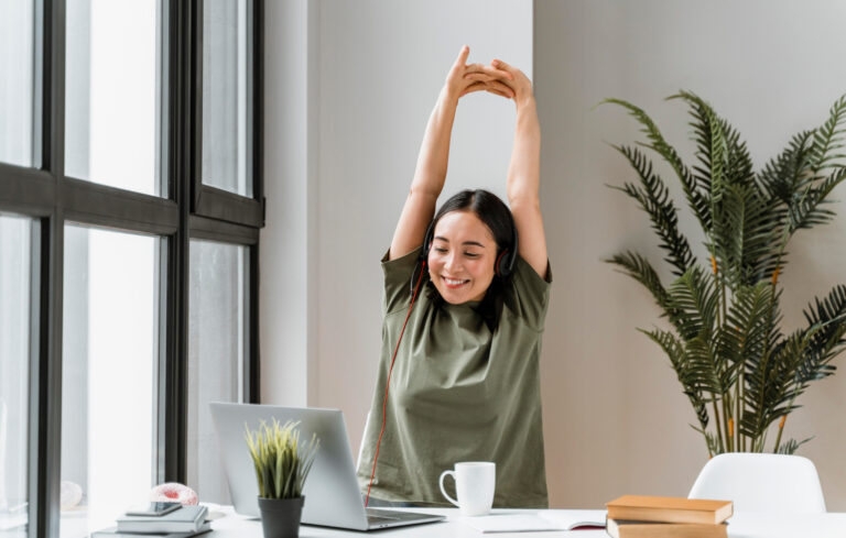 photo-of-woman-stretching-while-studying-for-inburgering-exam-with-green-plant-behind-her