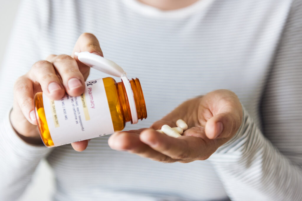 Dutch-woman-wearing-striped-shirt-shaking-paracetamol-pills-from-bottle-into-her-hand