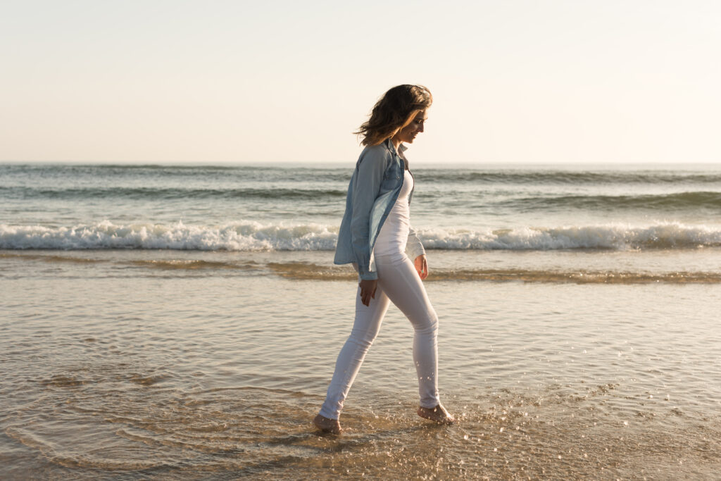 Woman-walking-on-the-beach-looking-relaxed-uitwaaien