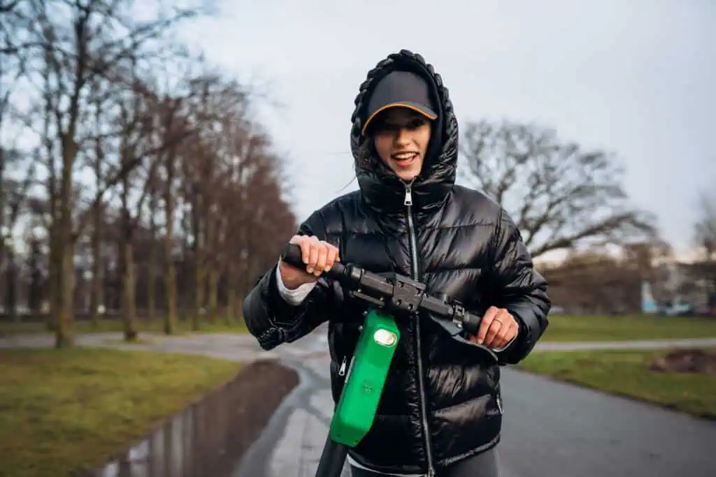 young-female-wearing-a-black-rainjacket-on-an-e-scooter-in-a-dutch-park