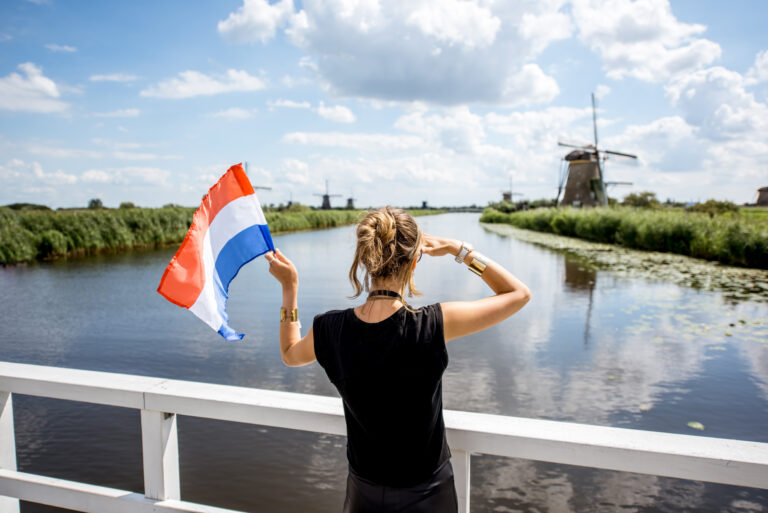 woman-with-dutch-residence-permit-waves-dutch-flag-in-front-of-several-windmills