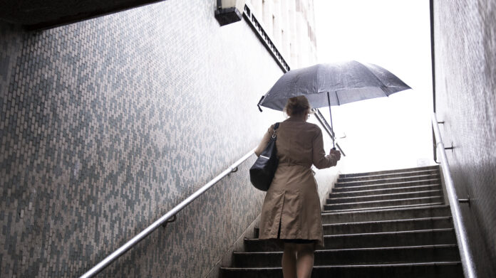 woman-with-umbrella-in-metro-going-up-in-rainy-weather-in-the-netherlands