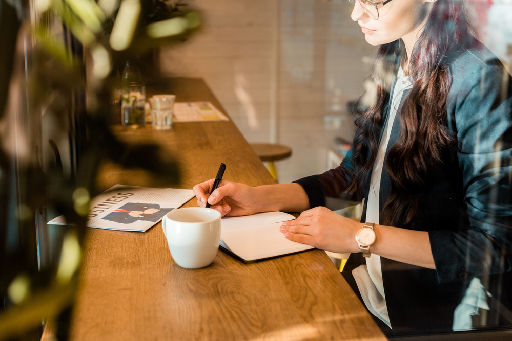 그녀 옆에 테이블에 앉아 커피 한 잔과 함께 카페에서 일하거나 공부하는 여성