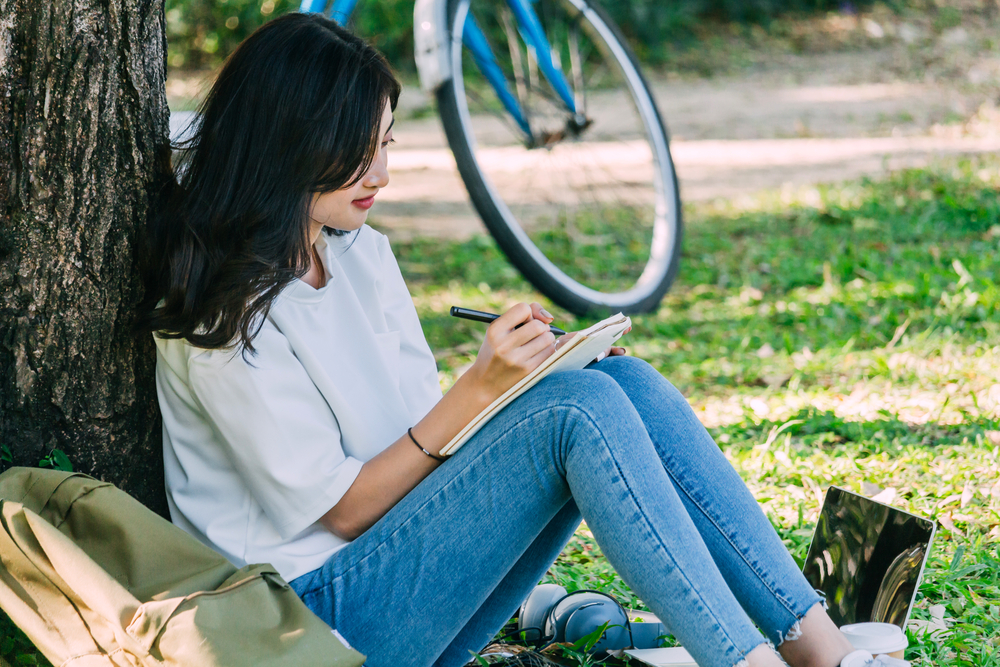 young-woman-writing-dutch-learning-goeals-in-notebook-outside