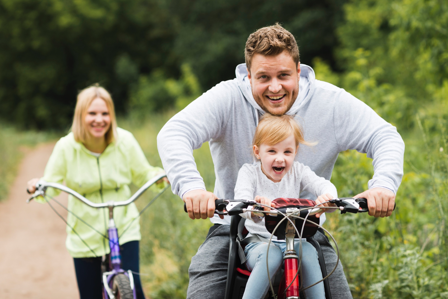 photo-of-happy-family-riding-bikes-down-forest-road
