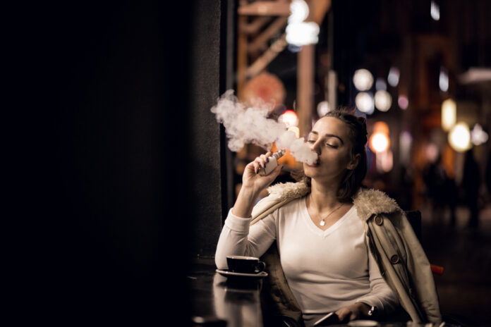 young-girl-vaping-electric-cigarette-outside-at-night