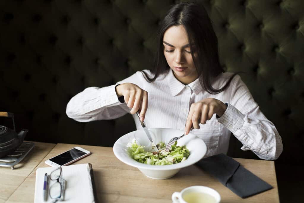 woman in business clothes eating salad for lunch at the office