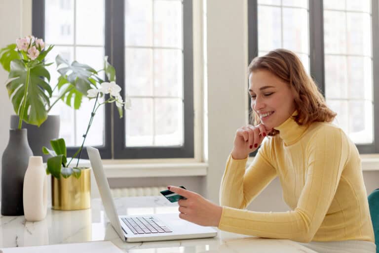 young-woman-in-a-yellow-jumper-smiles-at-her-dutch-bank-card-which-makes-life-in-the-netherlands-less-of-a-hassle