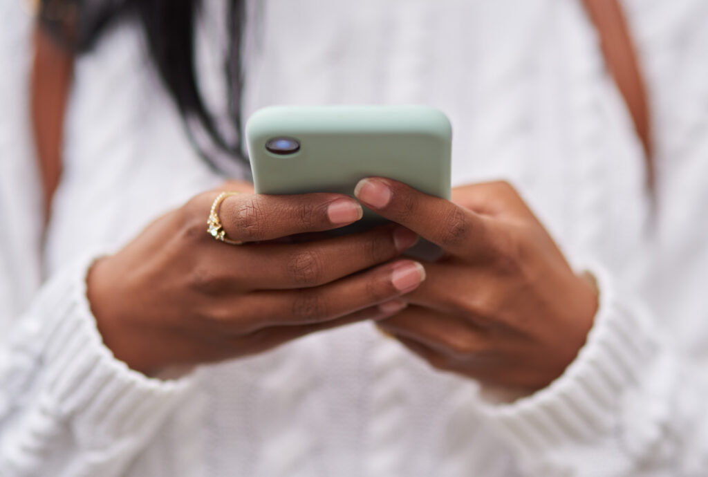 jovem-com-um-suéter-branco-e-um-anel-de-ouro-está-muito-focada-no-telefone