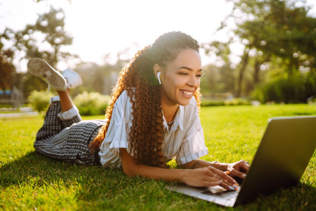 young-woman-sitting-in-green-grass-with-laptop-following-IU-MBA-online