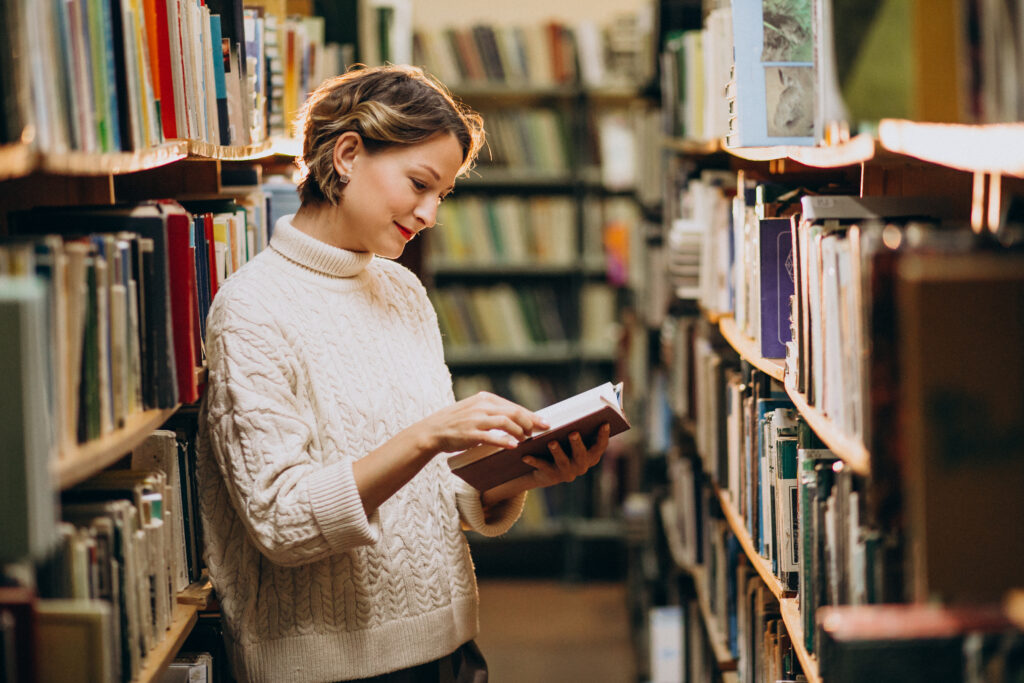 흰색 스웨터를 입고 서점에서 책을 읽는 젊은 여성