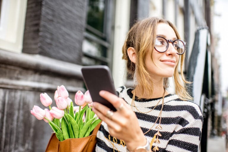 photo-of-woman-using-investment-app-on-phone-while-holding-tulips-in-netherlands