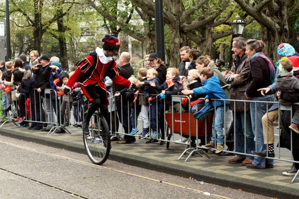 Zwarte Piet riding a unicycle in a parade in Amterstam